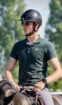 a young man wearing a helmet and riding a horse