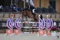 a woman riding a horse over an obstacle